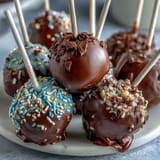 Festive graduation cake pops in school colors with shimmering gold sprinkles, perfect for celebrating academic achievements.  