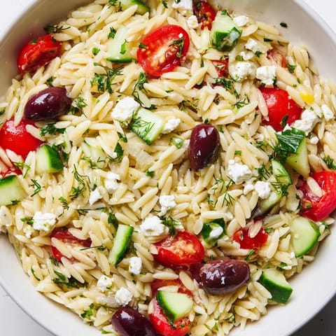 Chilled Greek orzo salad featuring tender pasta, crisp cucumber, juicy tomatoes, and briny feta, tossed with a bright lemon-oregano vinaigrette.