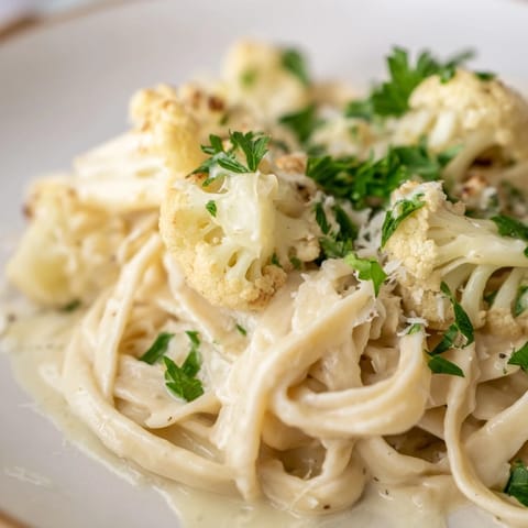 A skillet of homemade Roasted Cauliflower Alfredo features roasted cauliflower blended into a silky sauce over fettuccine.  