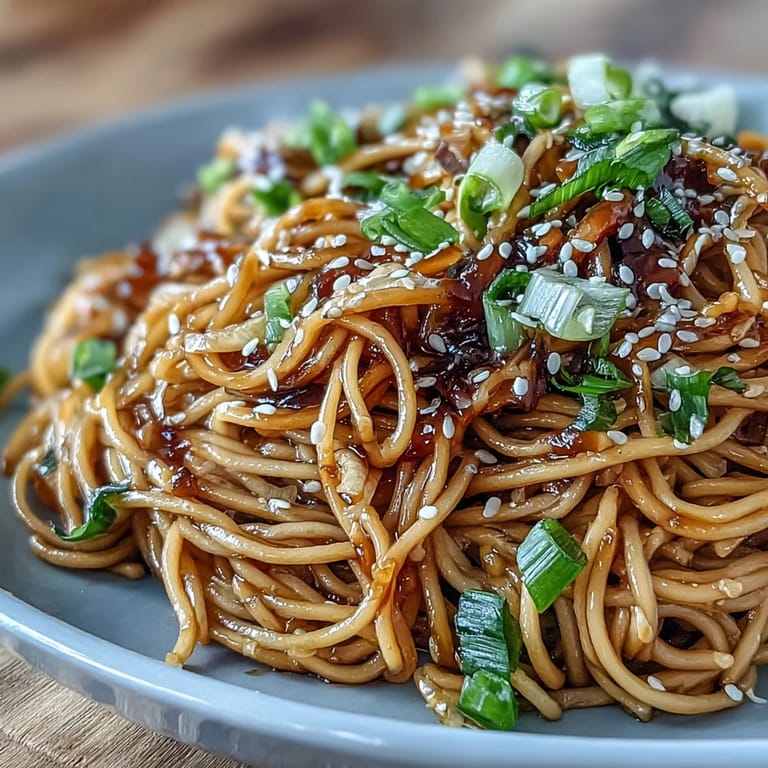 Quick and flavorful Asian Ginger Scallion Noodles with Soy Glaze, served hot with toasted sesame seeds and fresh cilantro for an umami-packed meal.