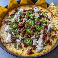 Festive Cinco de Mayo Loaded Queso Dip with chorizo, pico de gallo, and melted cheese in a cast iron skillet.